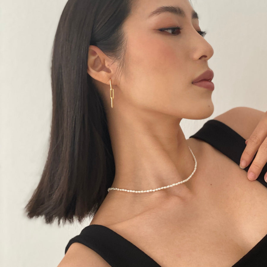 close up photo - girl wearing 18ct gold plated on 925 sterling silver paperclip link earrings set in cubic zirconia stone and freshwater seed pearl necklace
